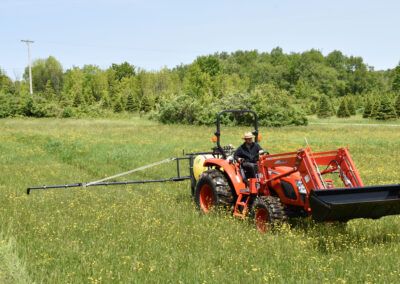 An Iva Sprayer in a field pulled by a KIOTI tractor.
