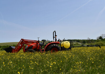 An Iva Sprayer in a field pulled by a KIOTI tractor.