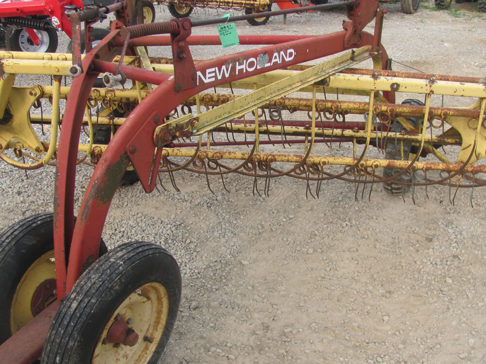 Used New Holland 256 Rollabar Rake with dolly wheels, in fair condition, some missing tines and worn bearings on the tooth arms.