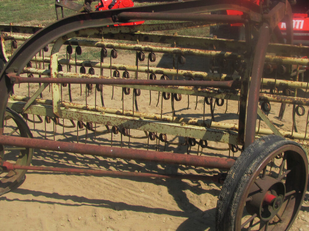 Used New Holland 56 Rola Bar Rake with steel tines, steel wheels with rubber, and some rust.