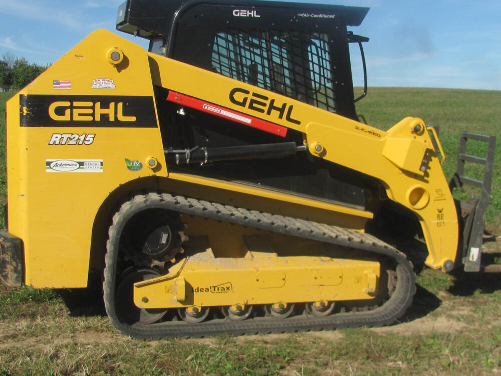 Used Gehl RT215 Track Skid Steer — 74 HP, joystick controls, 2-speed, enclosed cab with fold-up door, high-flow or standard auxiliary hydraulics, 3,000-lb rated lift, 9,899-lb operating weight, and an 80" smooth bucket, in good condition.