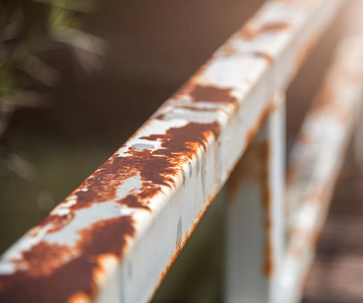 Rust forming on painted steel railing, showing how coatings fail and corrosion spreads.