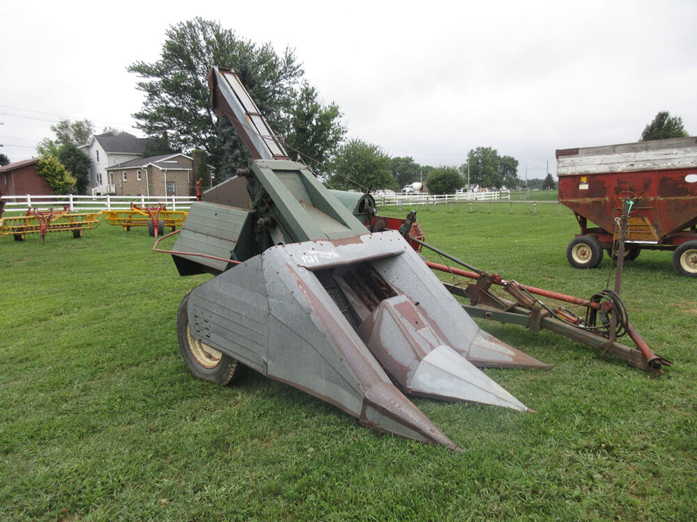 Used New Idea 324 corn picker with sheller, 2-row setup, large tires, lowered axles to raise picker, quick-hitch setup with pulley for easy unhook, serial #246583, and in good condition. Does not have a jack.