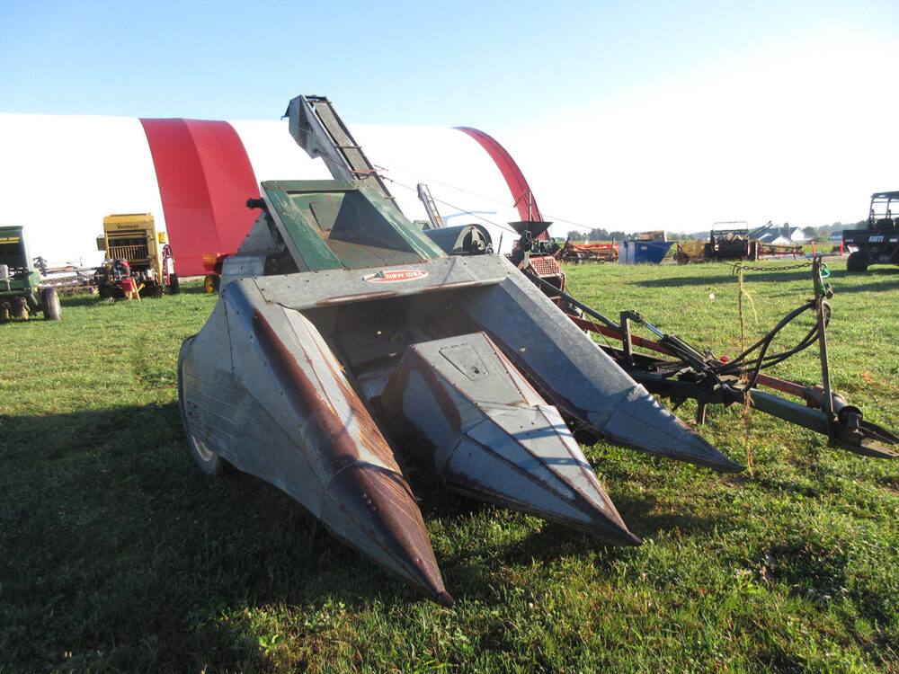 Used equipment: New Idea wide-row corn picker with 12-roll husking bed, in good condition, hydraulic hoses are worn but do not leak, fan belt is missing, rubber husking wheels are broken, serial number 197894